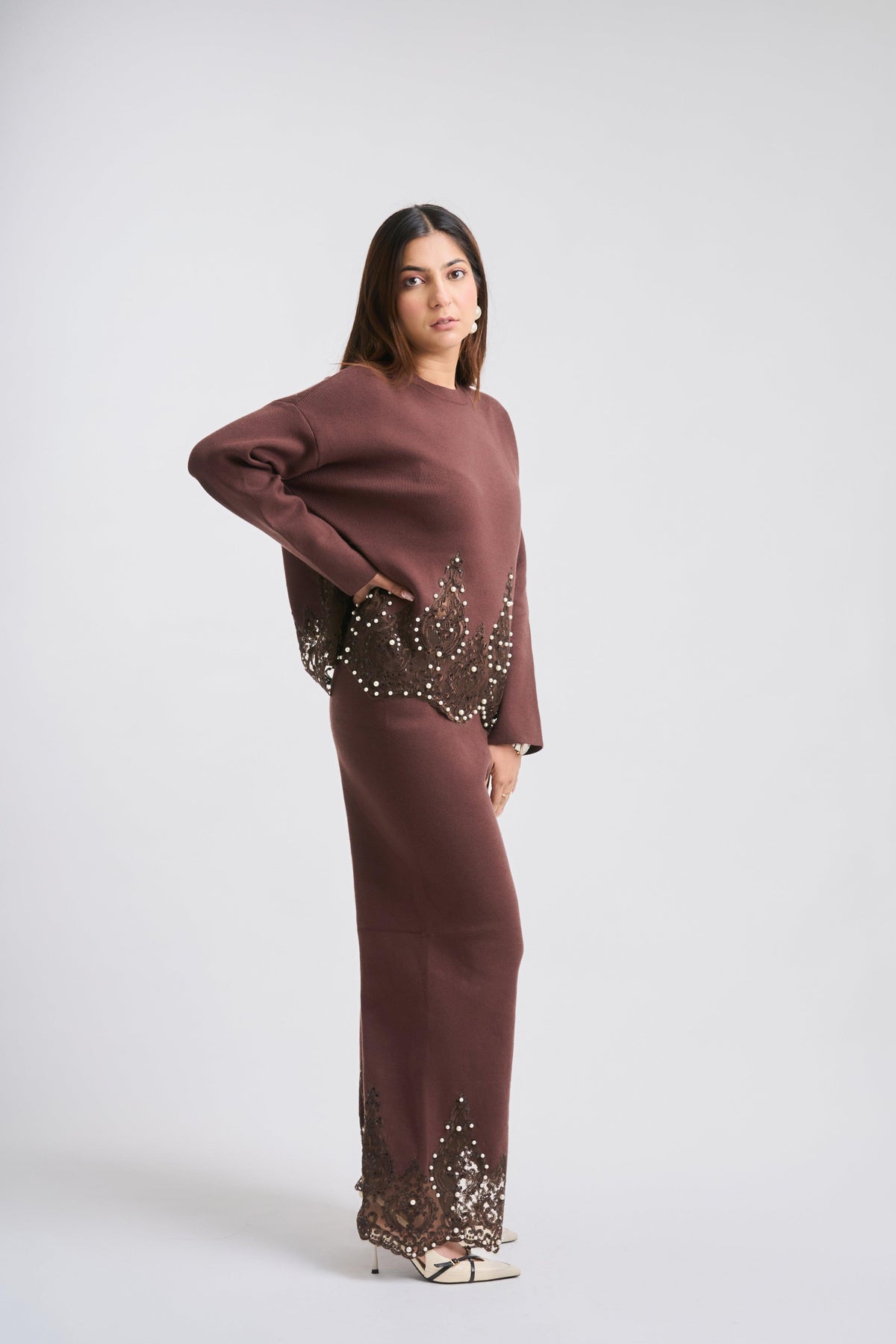Woman wearing a brown outfit with embellishments on a white background