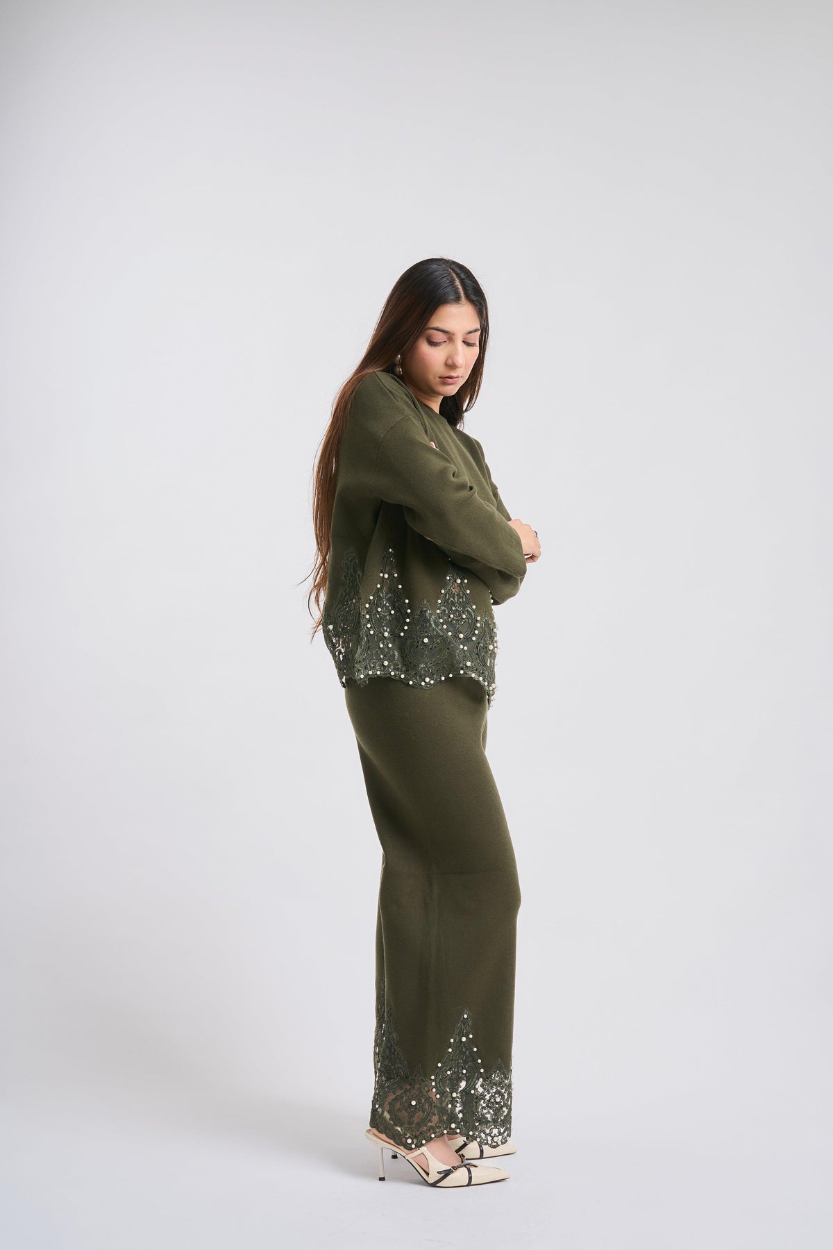 Woman wearing a green outfit with sequin details on a white background