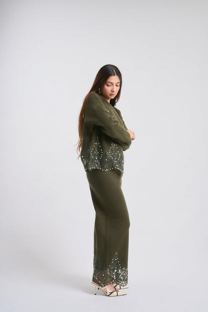 Woman wearing a green outfit with sequin details on a white background