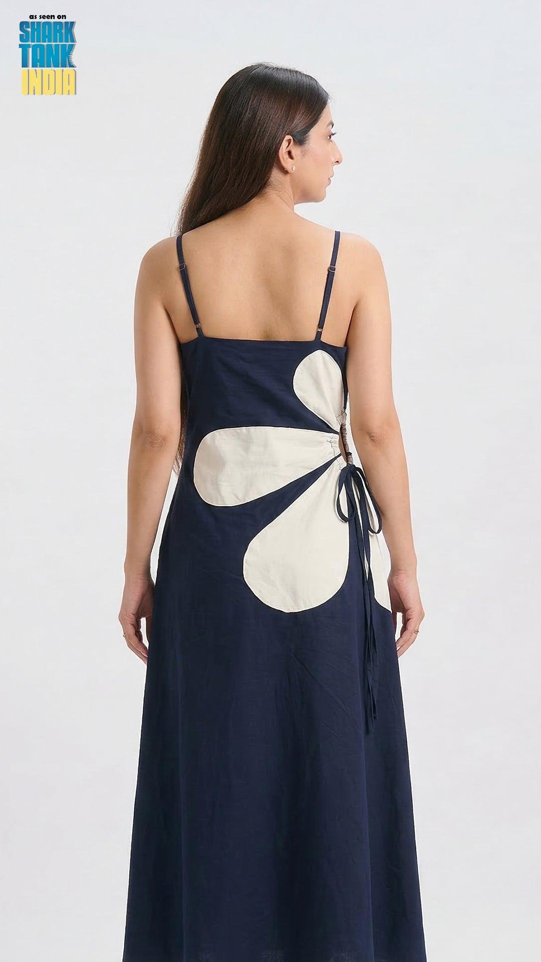 Woman wearing a navy blue dress with a large white floral pattern on a white background