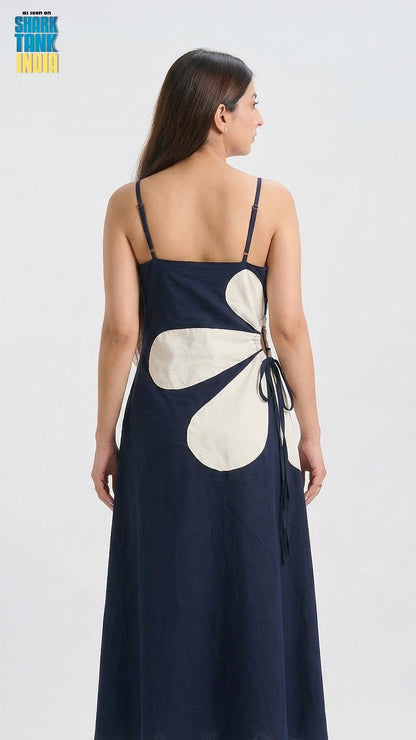Woman wearing a navy blue dress with a large white floral pattern on a white background
