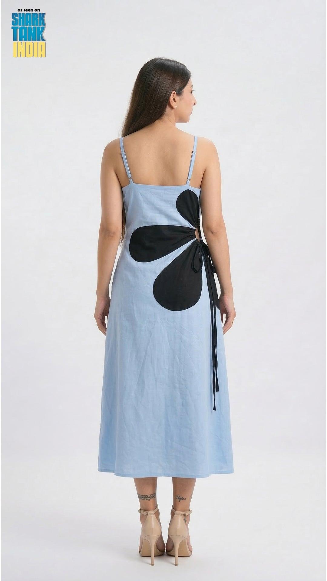 Woman wearing a light blue dress with a black flower design on a white background