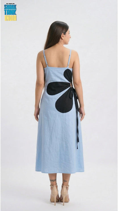 Woman wearing a light blue dress with a black flower design on a white background