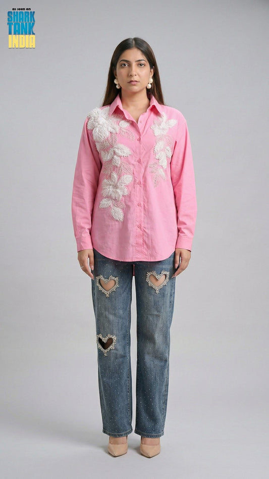 Woman wearing a pink shirt with floral patterns and blue jeans with heart shapes on a gray background