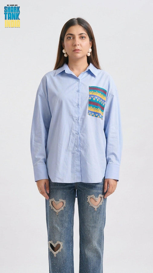 Woman wearing a light blue shirt with a colorful patch on a white background