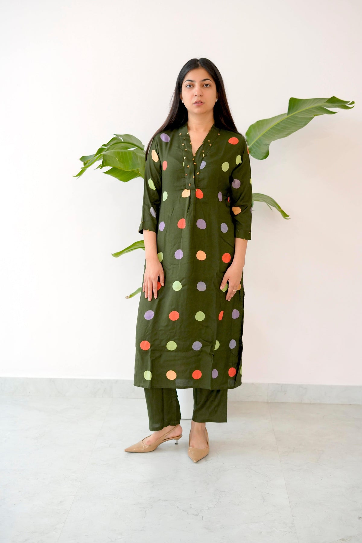 Woman wearing a green polka dot kurta with pants against a white background