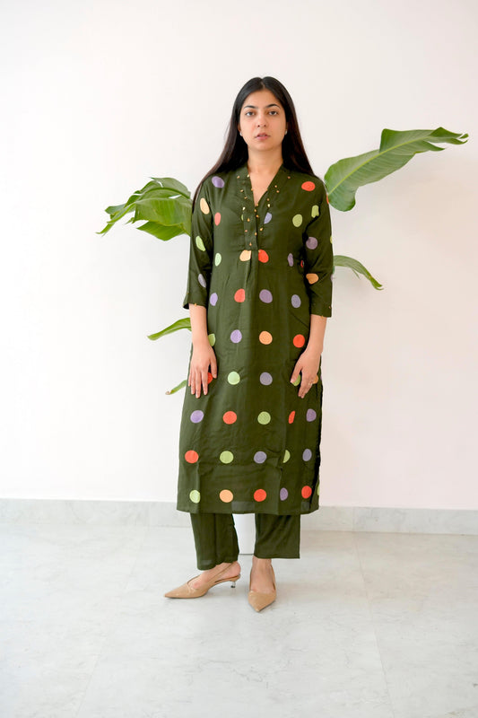 Woman wearing a green polka dot kurta with pants against a white background