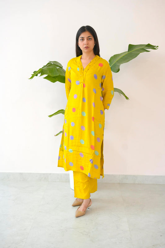Woman wearing a yellow polka dot kurta with matching pants against a white background
