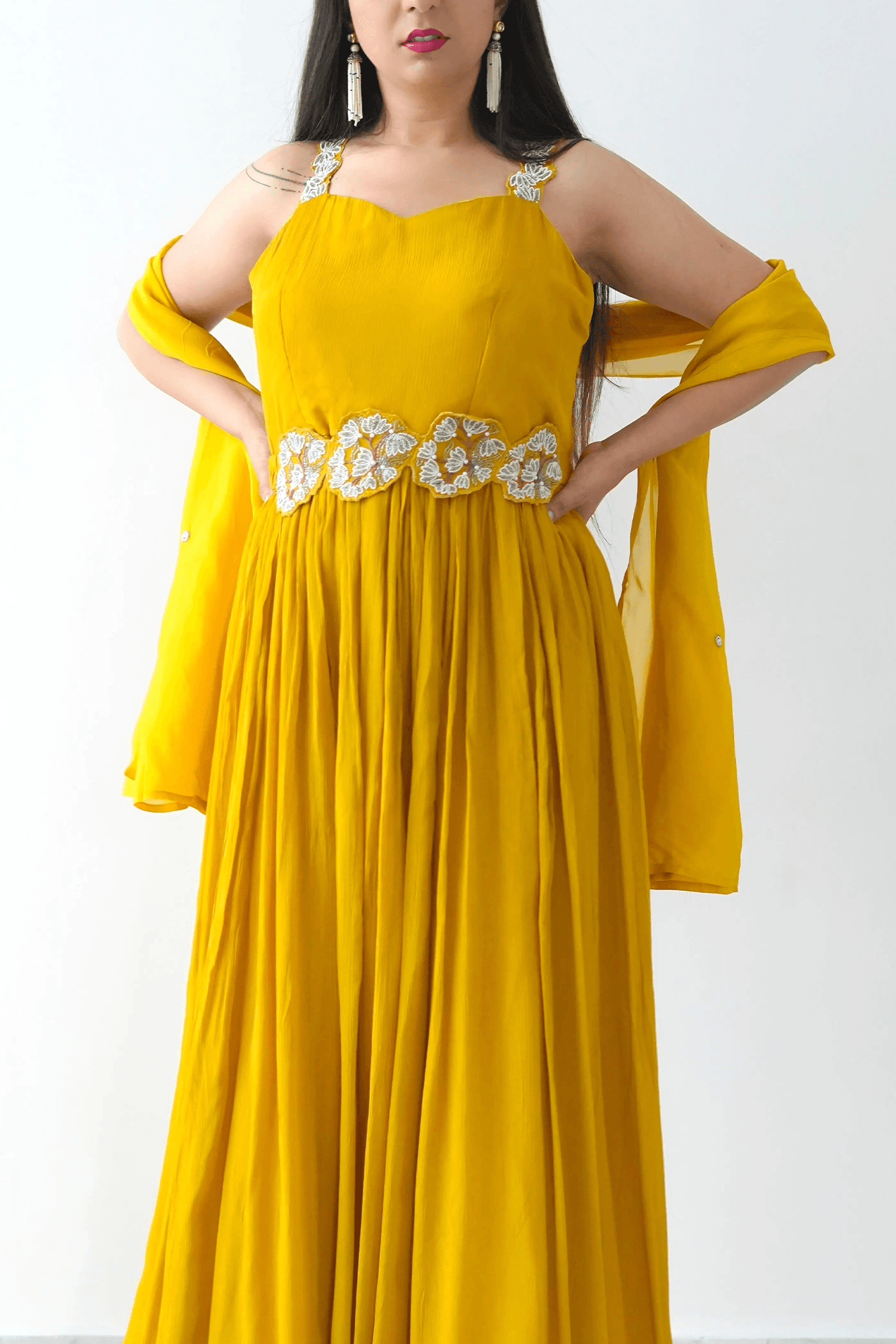 Woman wearing a yellow dress with floral embellishments on a white background