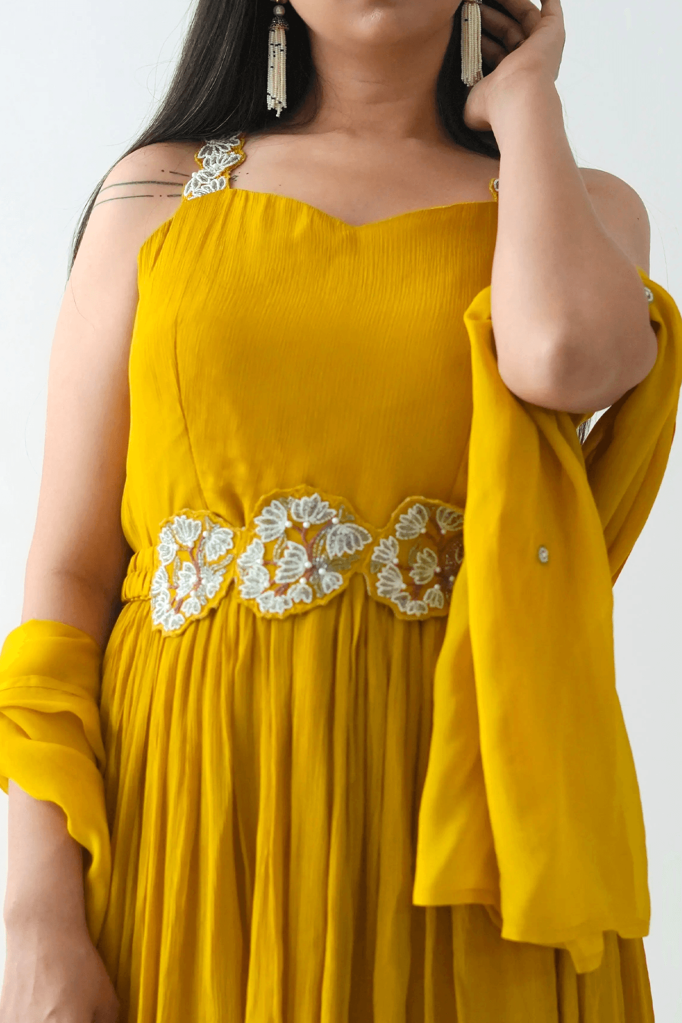 Yellow dress with floral embroidery on a plain background