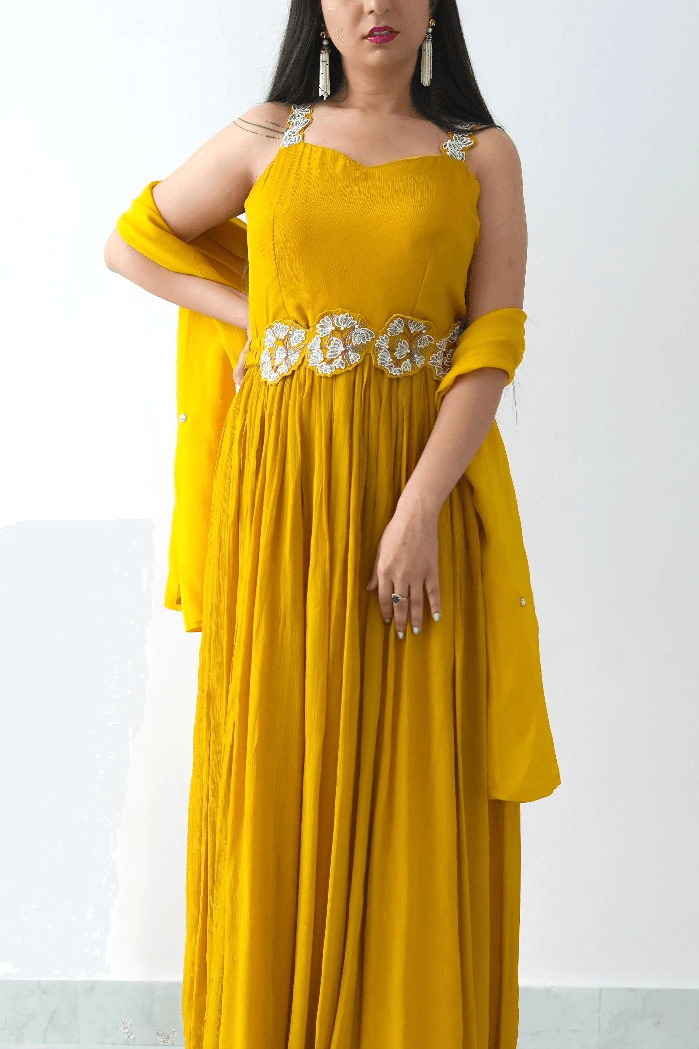 Woman wearing a yellow dress with floral details on a white background