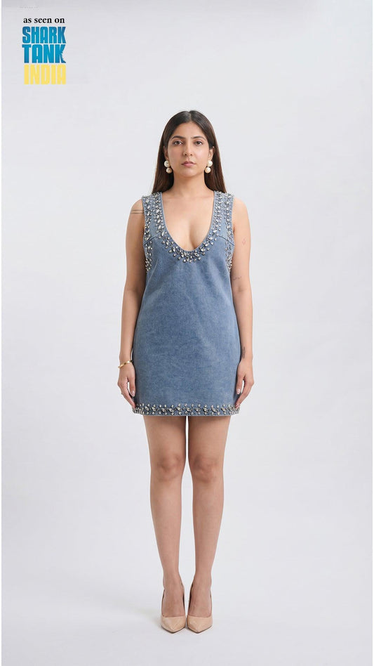 Woman wearing a blue dress with embellishments on a white background, featuring 'Shark Tank' branding.