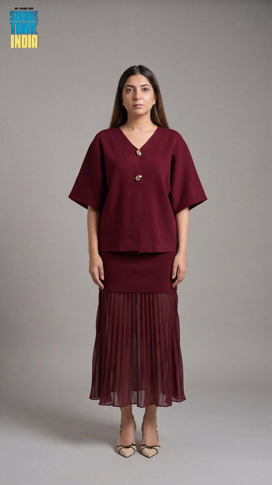 Woman wearing a burgundy outfit with a top and skirt against a gray background