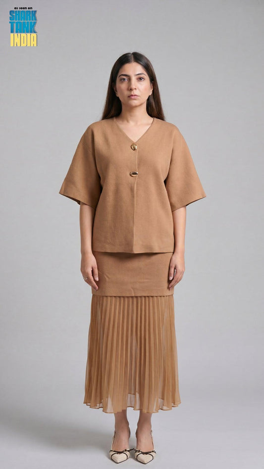 Woman wearing a brown outfit with a pleated skirt on a gray background