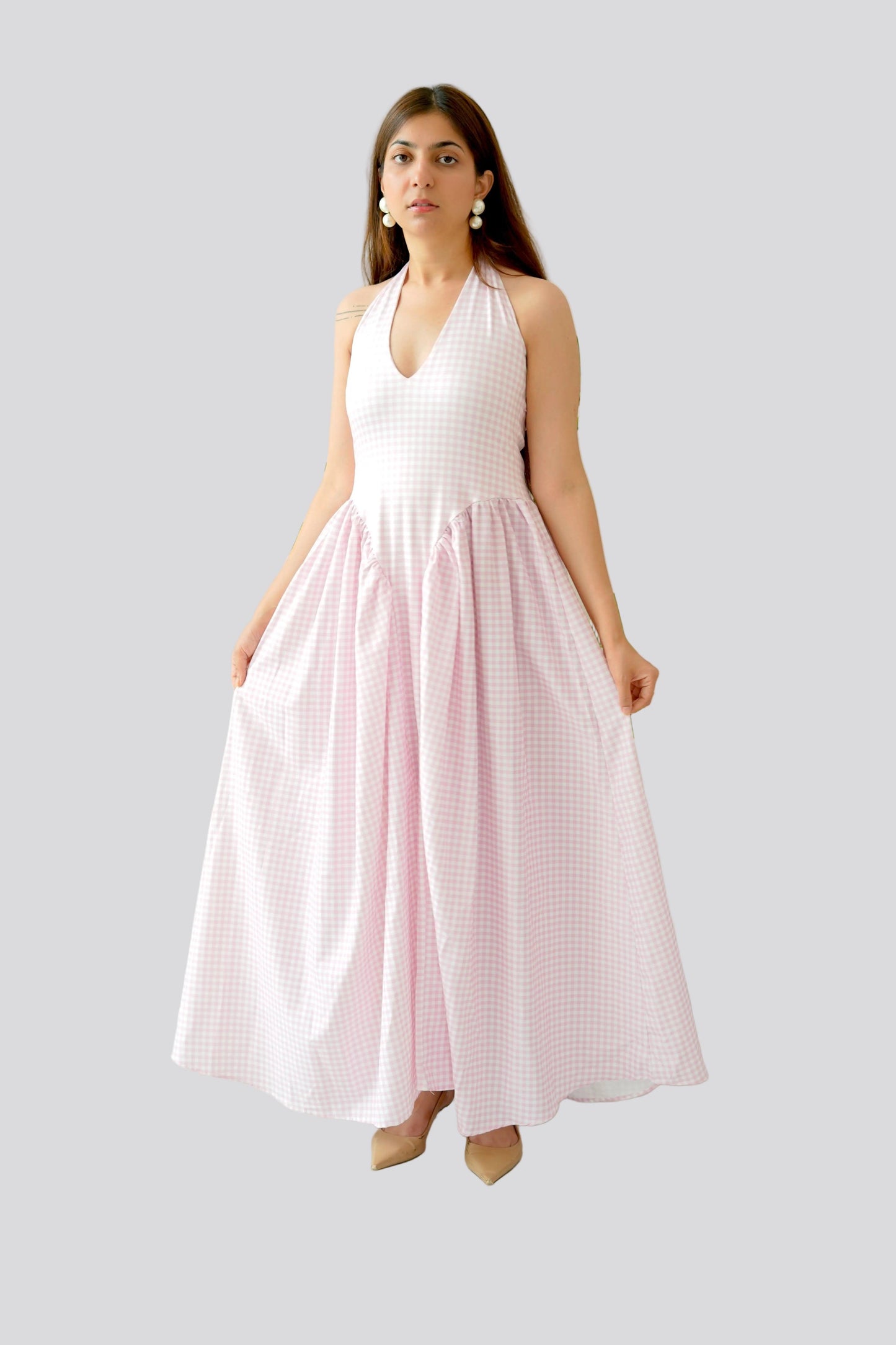 Woman wearing a white halter top and pink checkered skirt on a light gray background