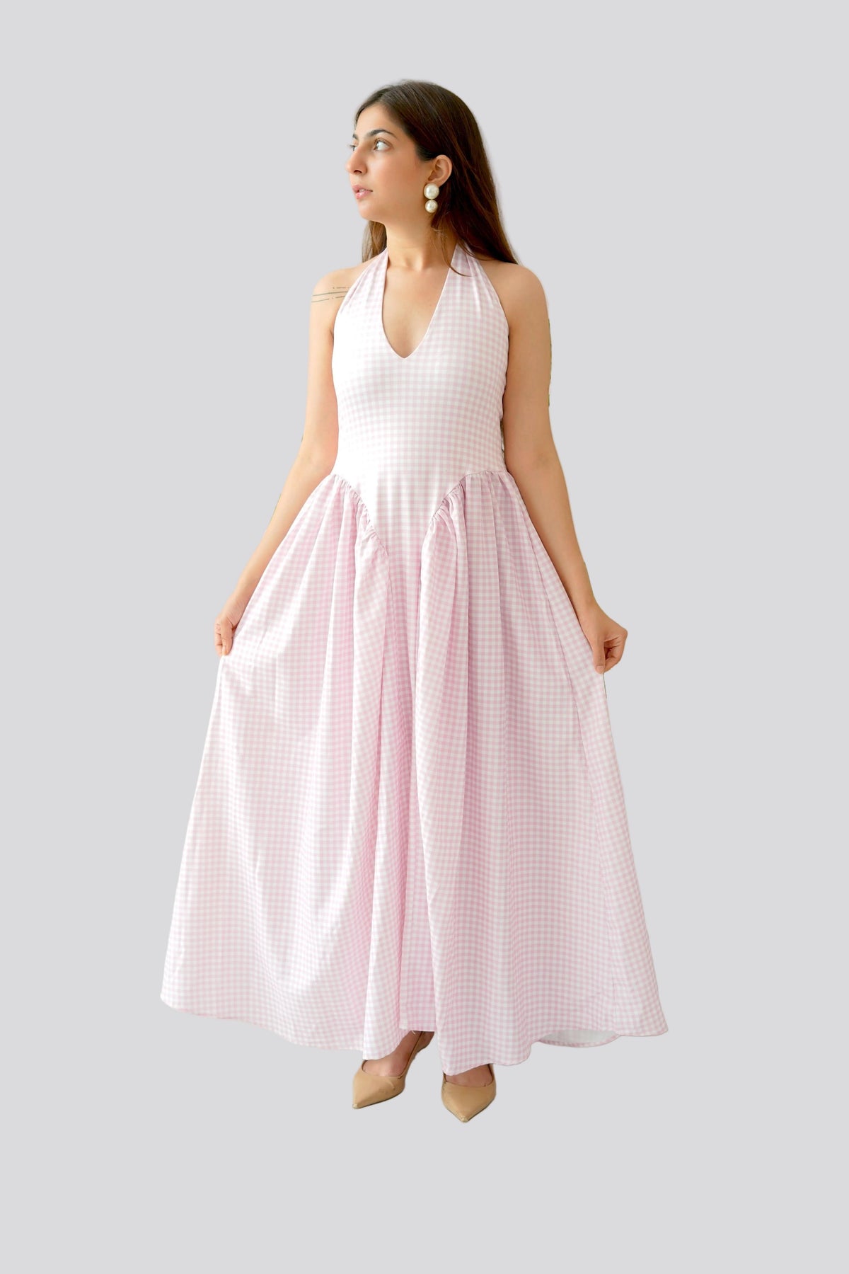 Woman wearing a white top and pink skirt on a gray background