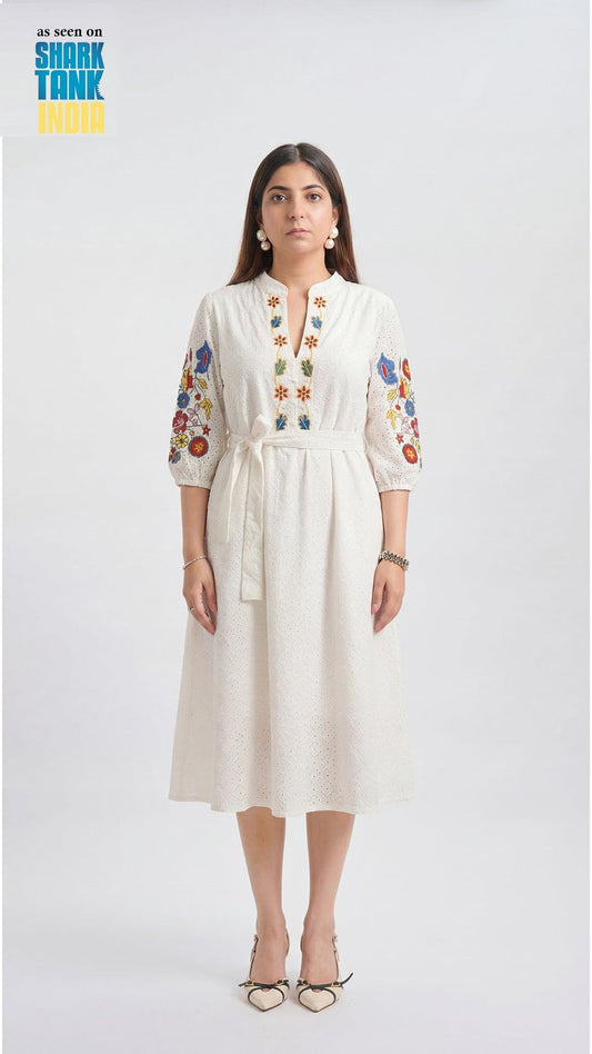 Woman wearing a white dress with floral embroidery on a white background