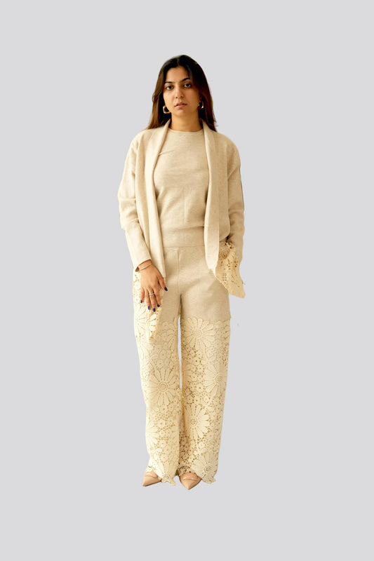 Woman wearing a beige outfit with a plain background and plants.