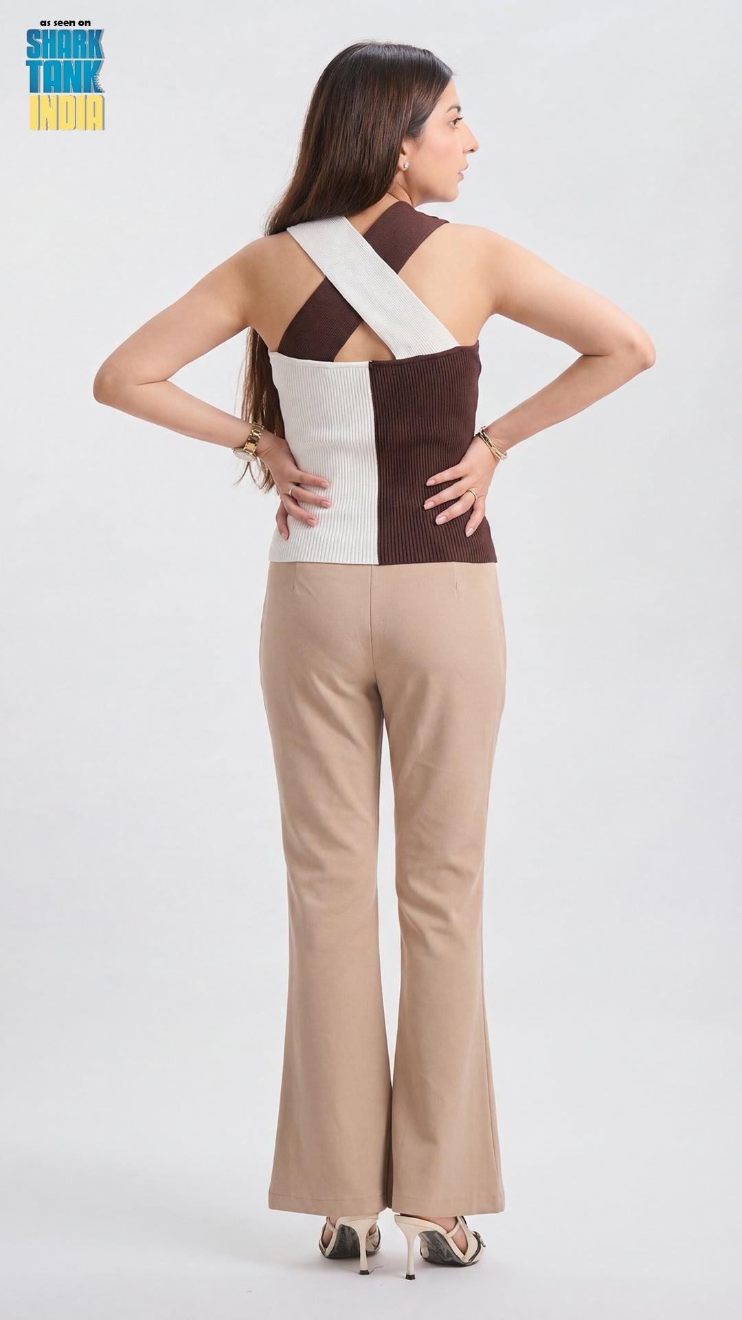 Woman wearing a two-tone jumpsuit with a white and brown color scheme on a plain background.