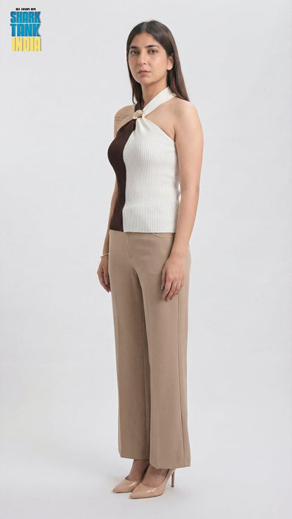 Woman wearing a white and brown top with beige pants on a white background
