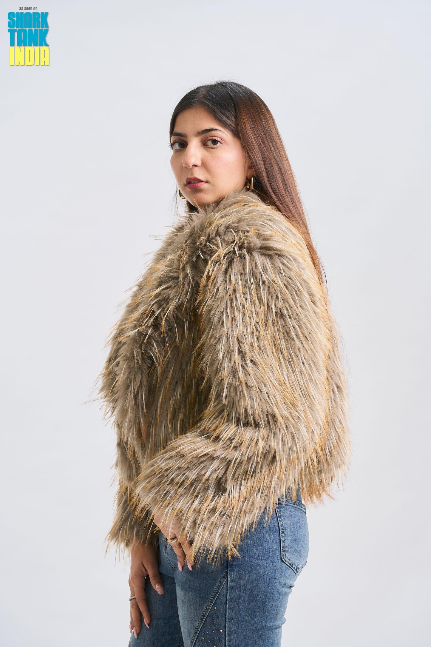 Woman wearing a fluffy beige jacket against a white background