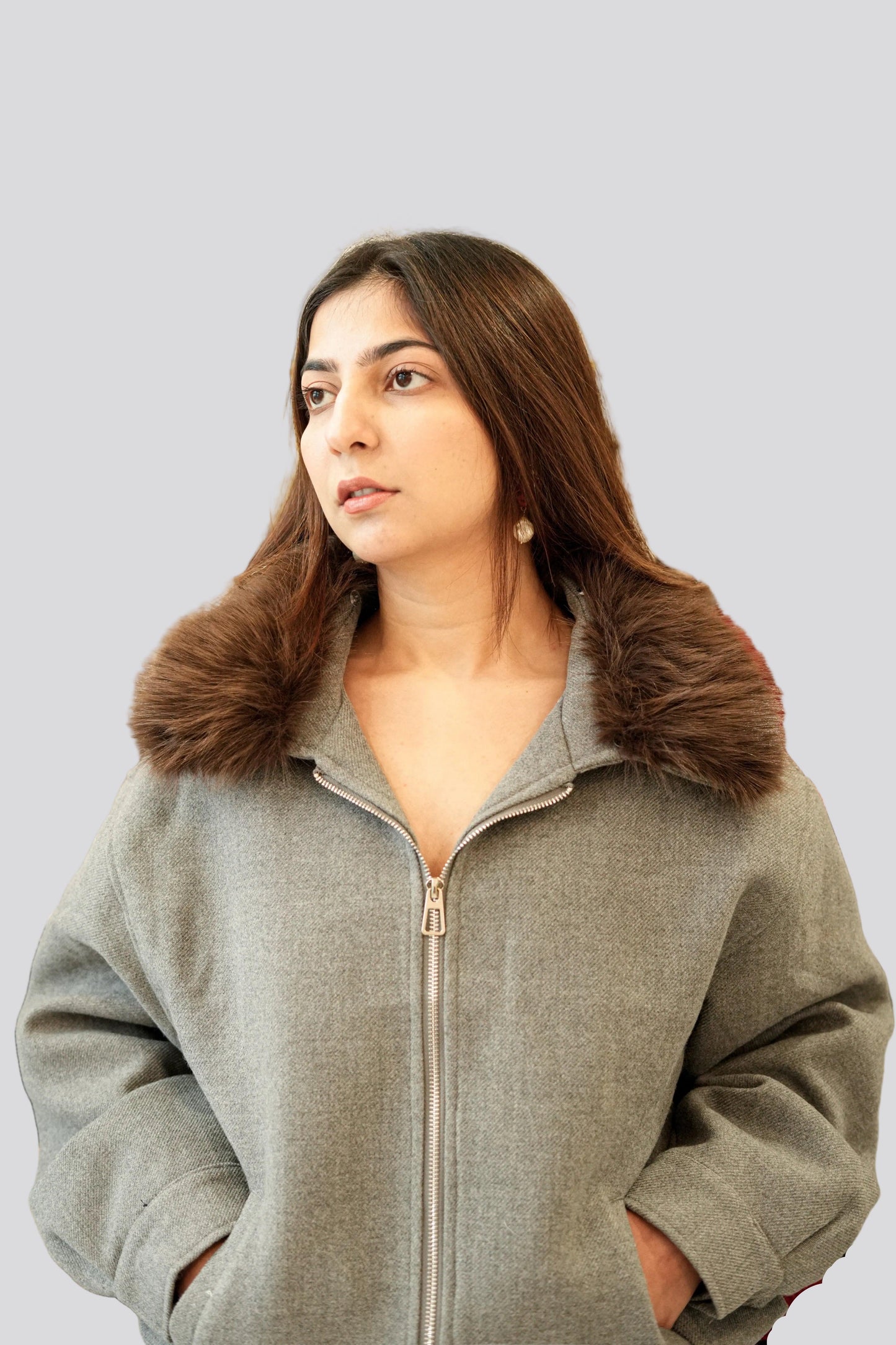 Woman wearing a gray jacket with a fur collar on a light gray background