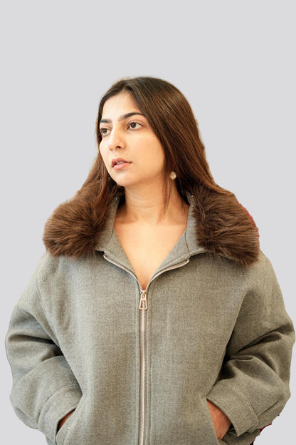 Woman wearing a gray jacket with a fur collar on a light gray background