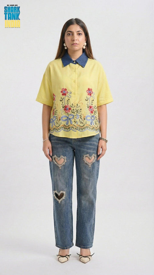 Woman wearing a yellow embroidered shirt and blue jeans on a white background