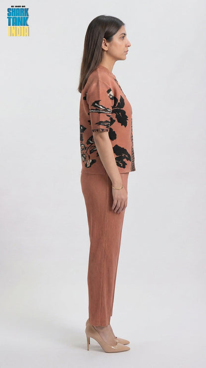 Woman wearing a pink outfit with black floral patterns on a white background