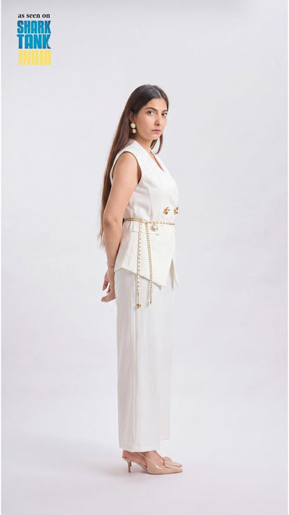Woman wearing a white outfit with gold accents on a plain background