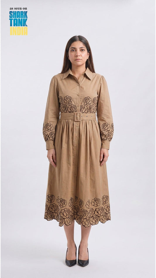 Woman wearing a beige dress with floral embroidery on a white background