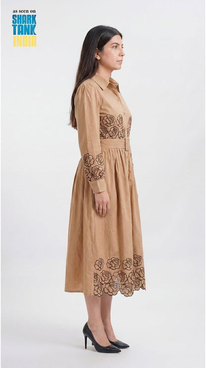 Woman wearing a beige dress with floral embroidery on a white background