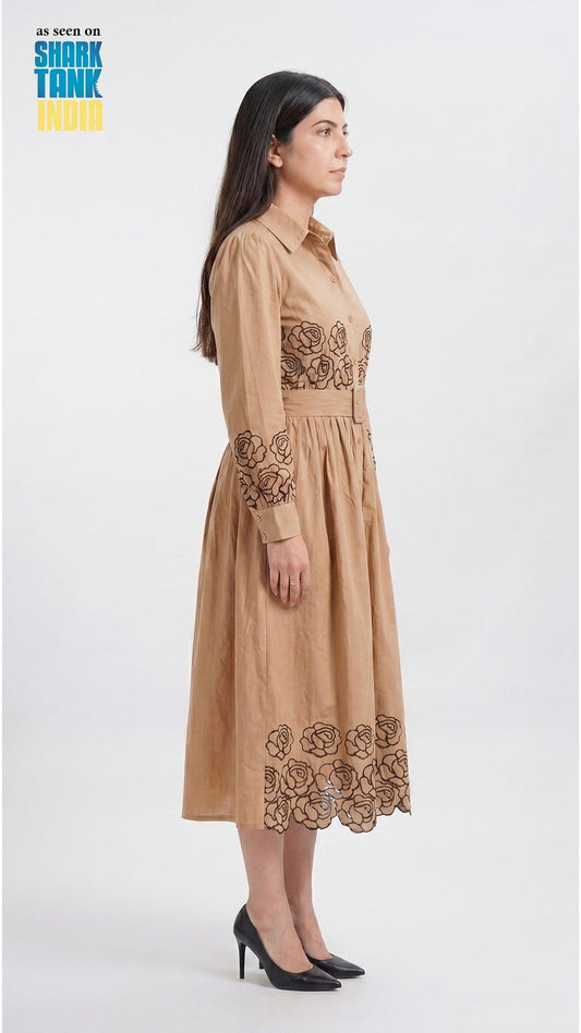 Woman wearing a beige dress with floral embroidery on a white background