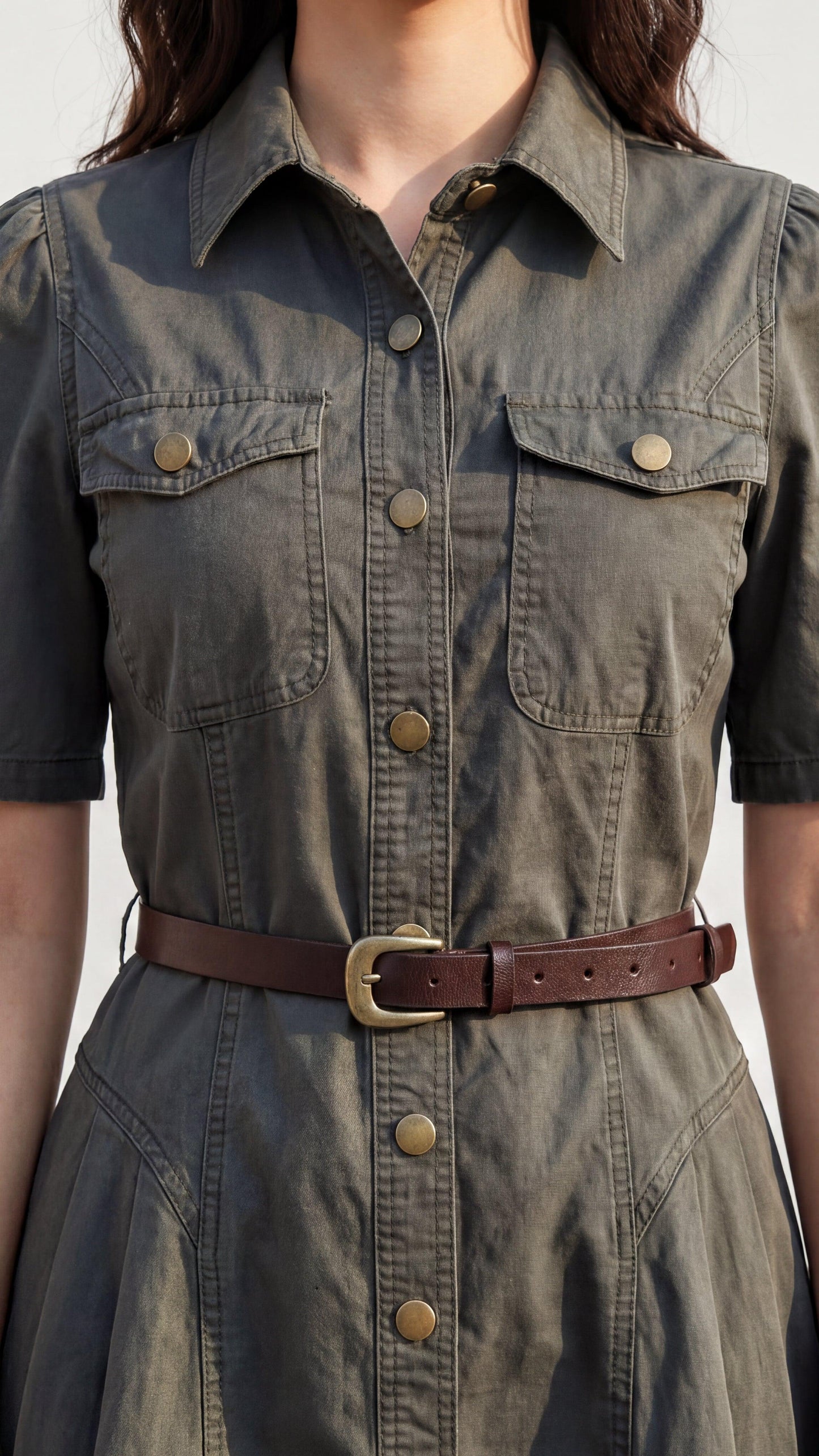 Green denim dress with brown belt on a neutral background