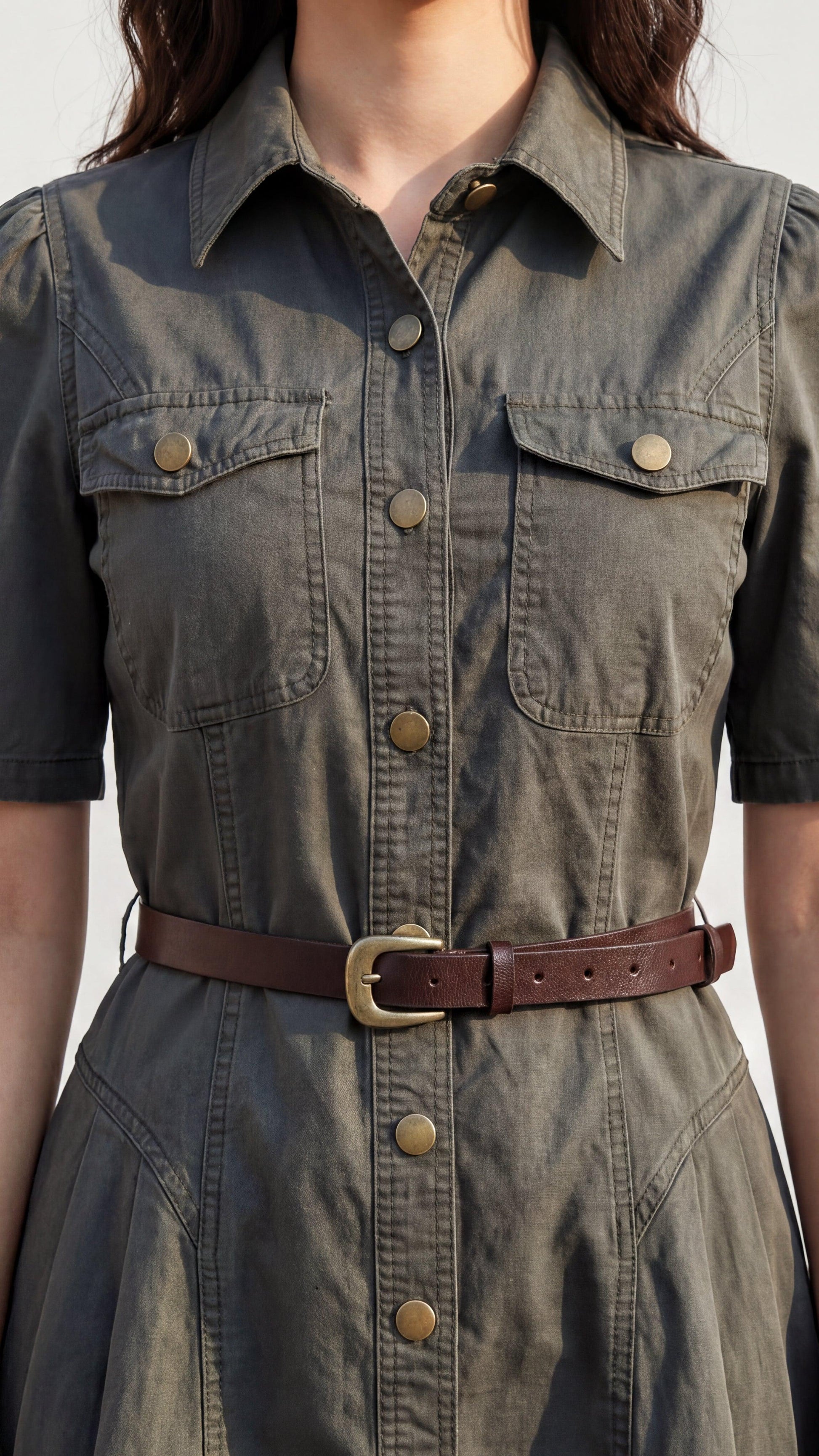 Green denim dress with brown belt on a neutral background