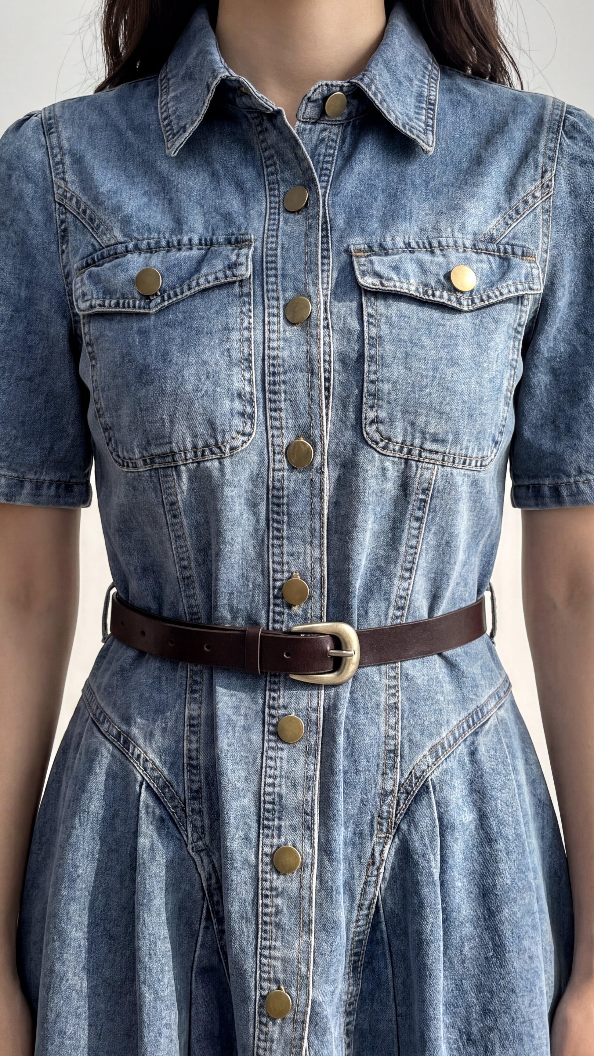 Denim jumpsuit with a belt on a neutral background