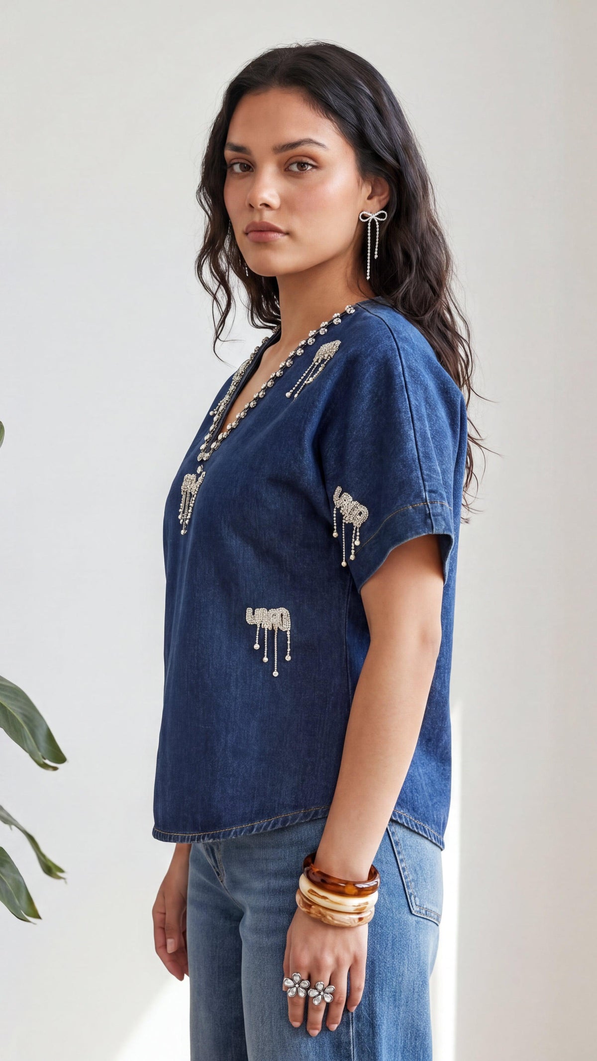 Woman wearing a blue denim top with decorative elements on a plain background