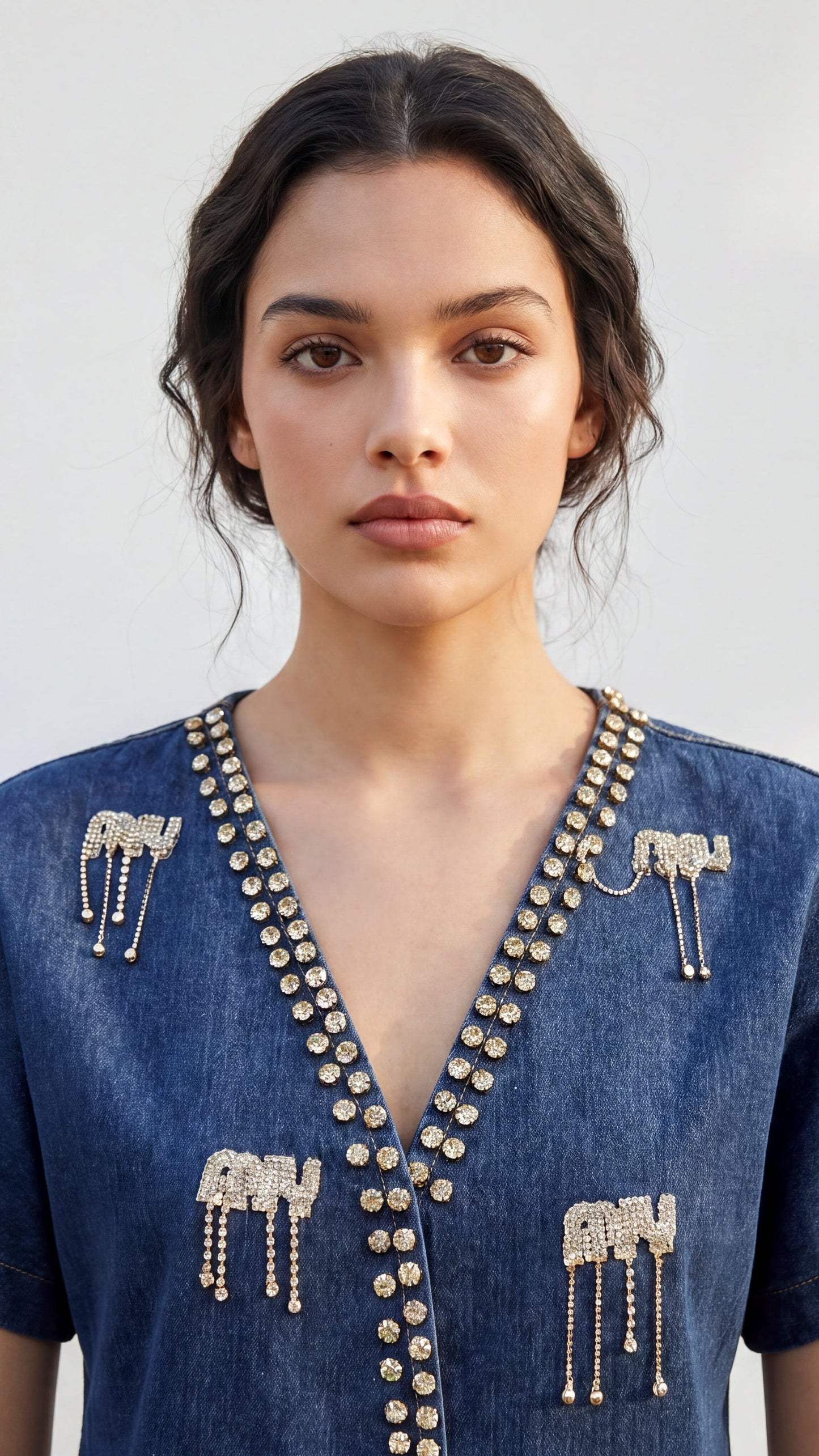 Woman wearing a blue dress with gold embellishments against a white background