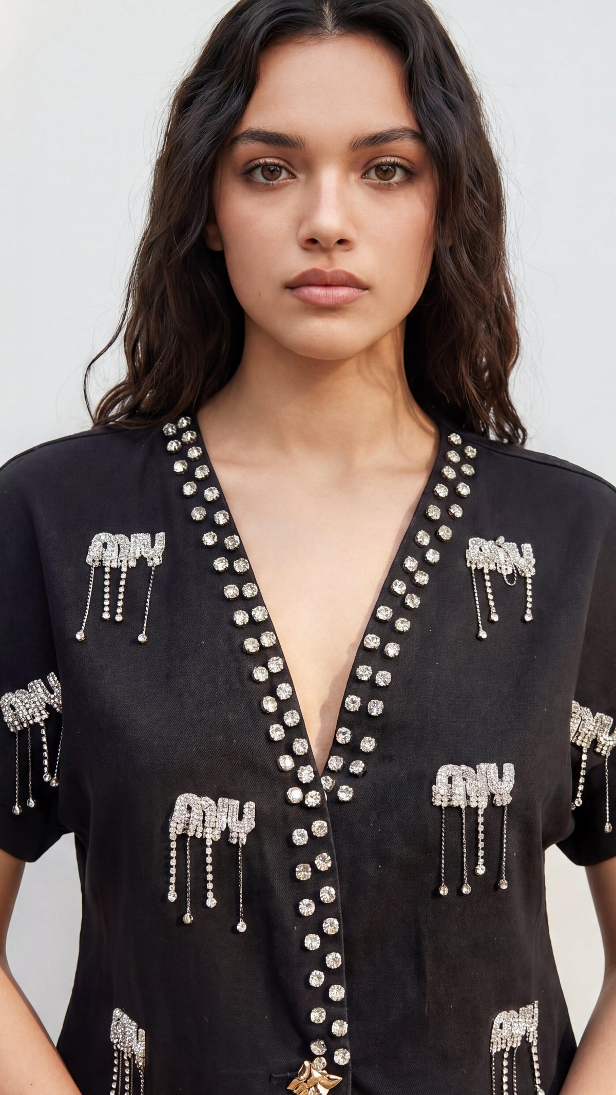 Woman wearing a black top with decorative elements against a plain background