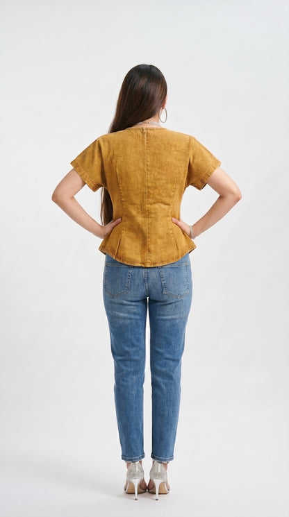 Woman wearing a mustard yellow top and blue jeans on a white background