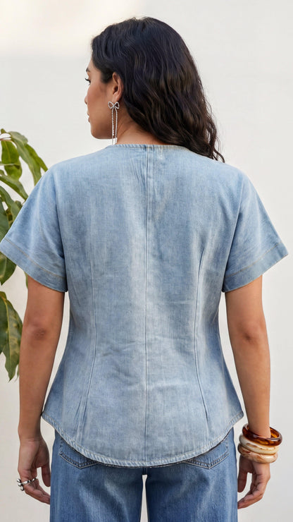 Woman wearing a light blue denim top and jeans against a white background