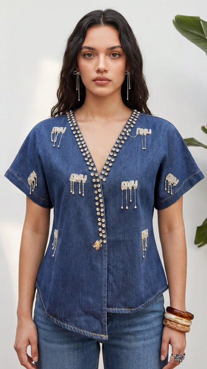 Woman wearing a blue denim blouse with intricate patterns and embellishments.