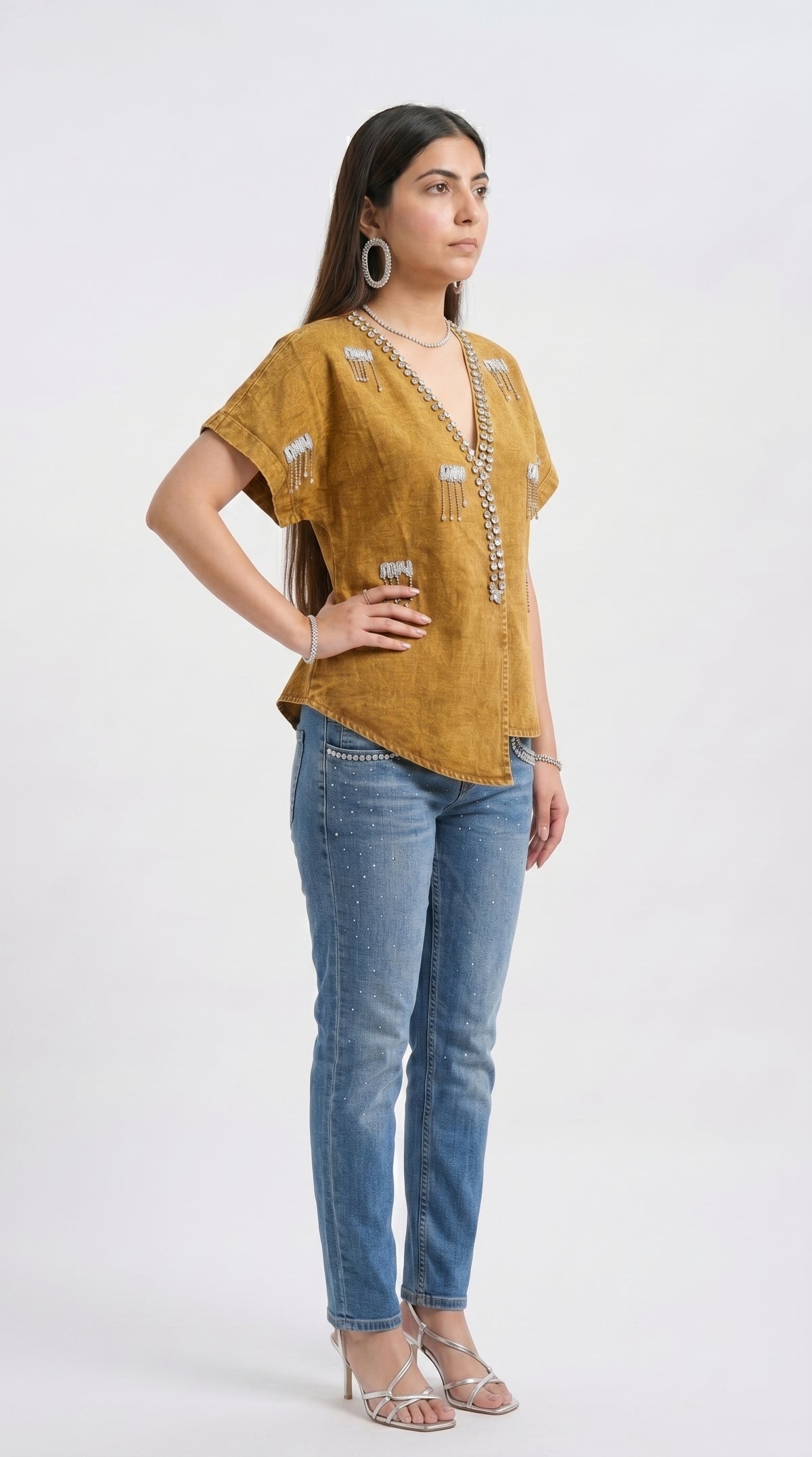 Woman wearing a mustard yellow top and blue jeans on a white background