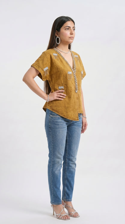 Woman wearing a mustard yellow top and blue jeans on a white background