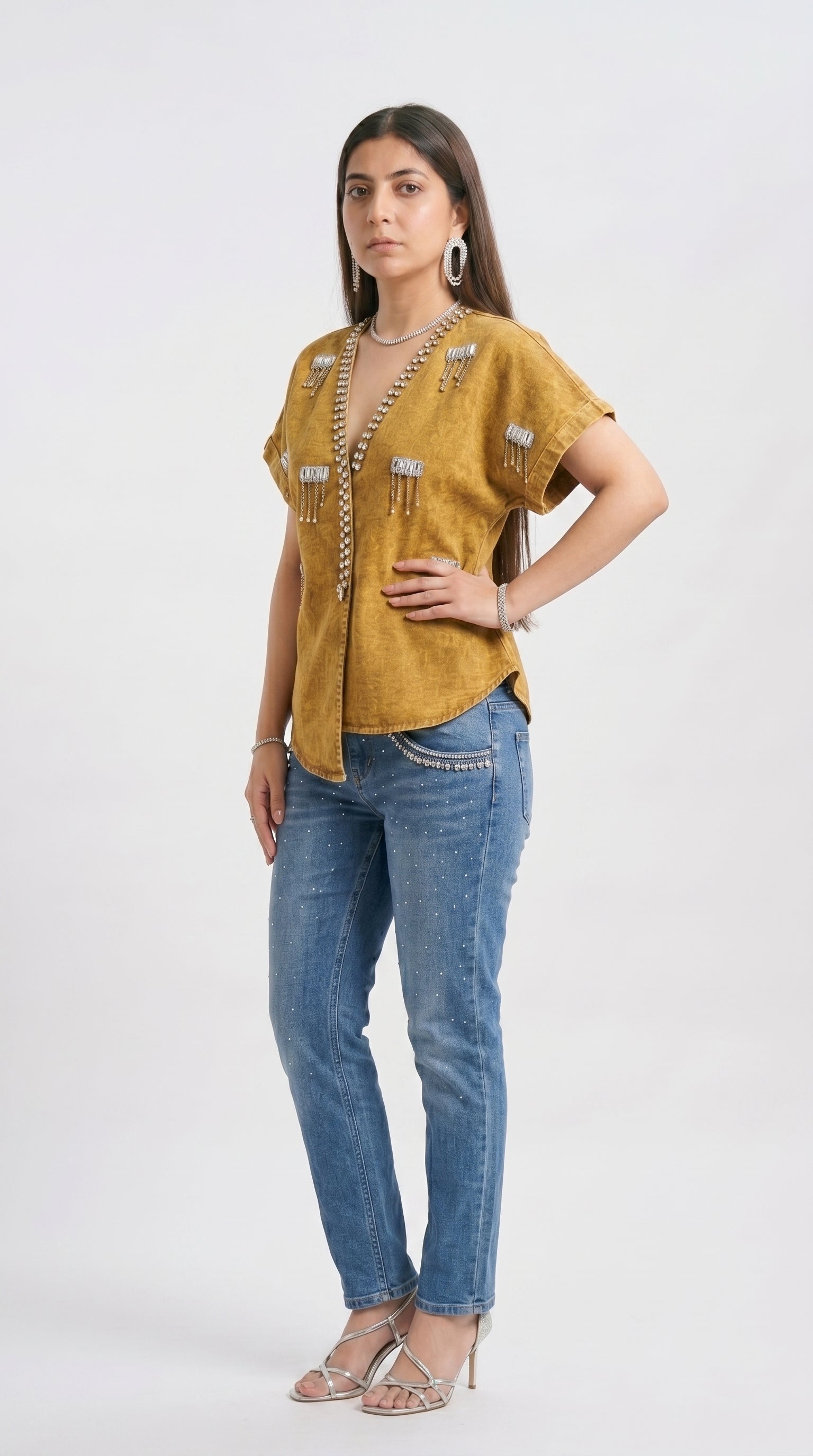 Woman wearing a mustard yellow top and blue jeans on a white background
