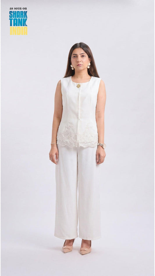 Woman wearing a white sleeveless top and wide-leg pants on a white background