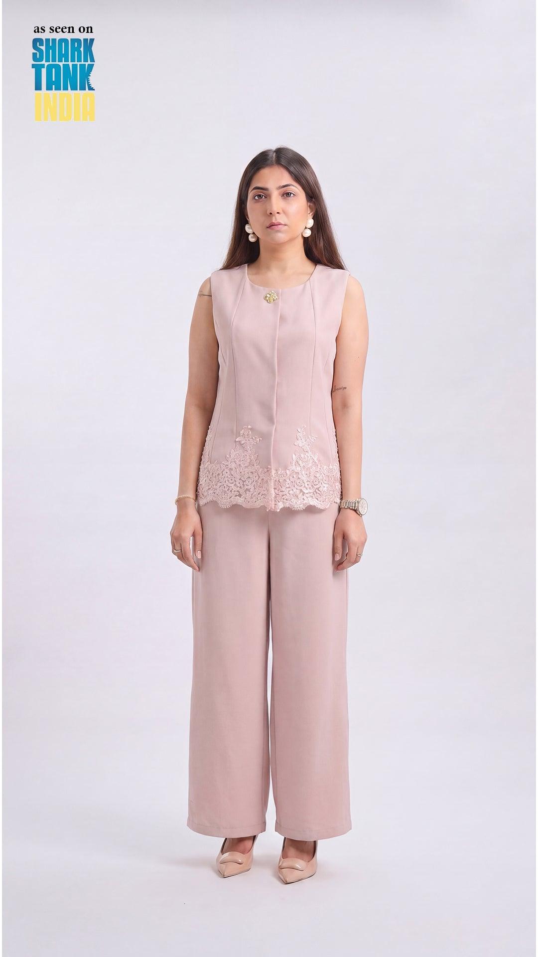 Woman wearing a light pink sleeveless top and wide-leg pants on a white background
