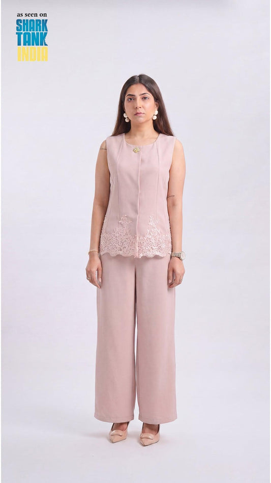 Woman wearing a light pink sleeveless top and wide-leg pants on a white background
