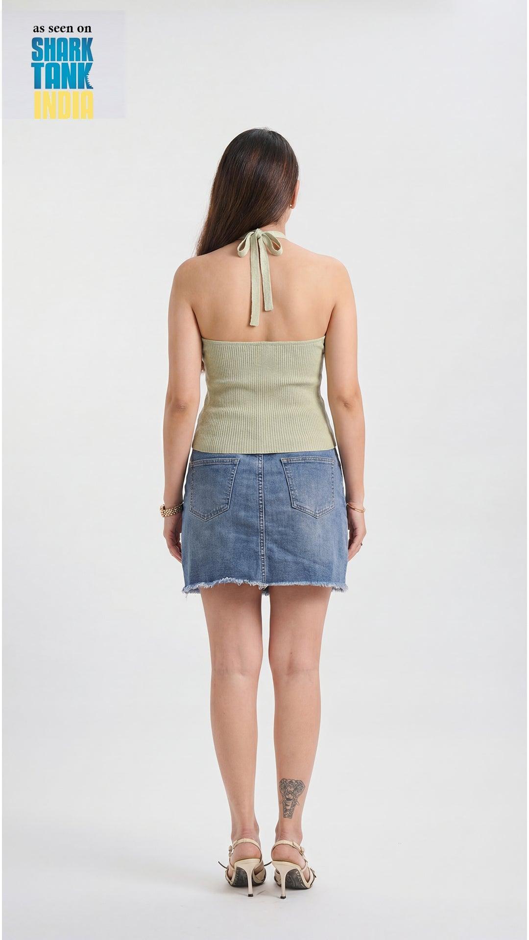 Woman wearing a green top and denim skirt on a white background