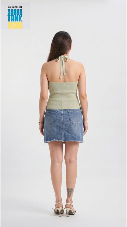 Woman wearing a green top and denim skirt on a white background